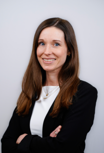 Porträtfoto einer Frau mit langen braunen Haaren und verschränkten Armen.